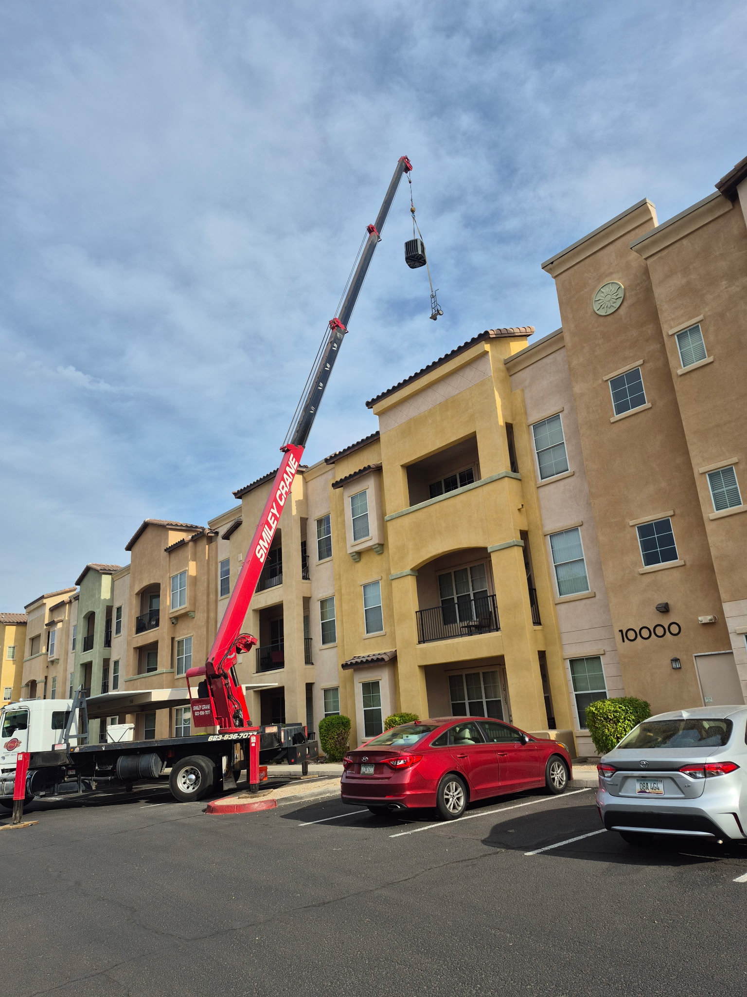 Crane lifting HVAC equipment onto a multi-story building